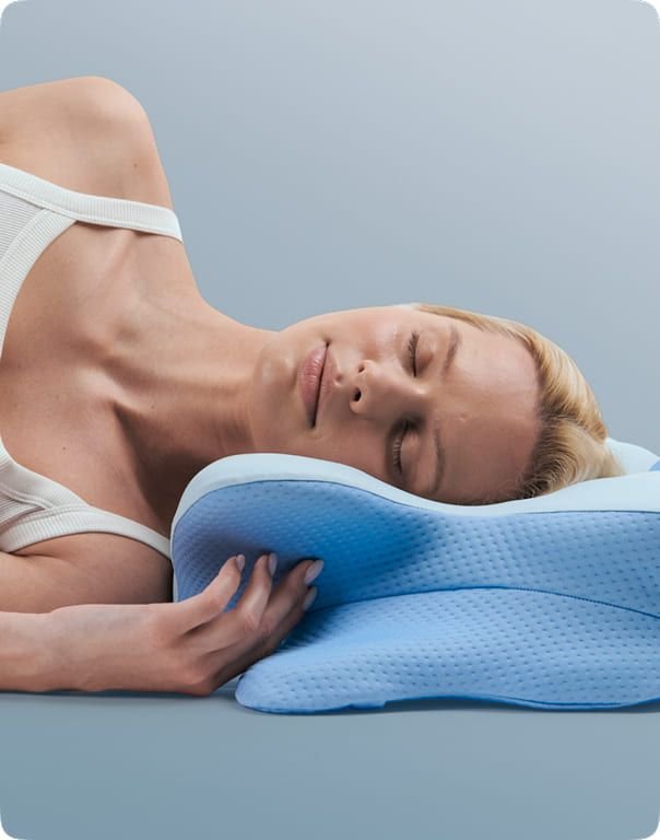 Side sleeper with her head on the cervical contour pillow and her hand resting against the pillow's raised side lobe